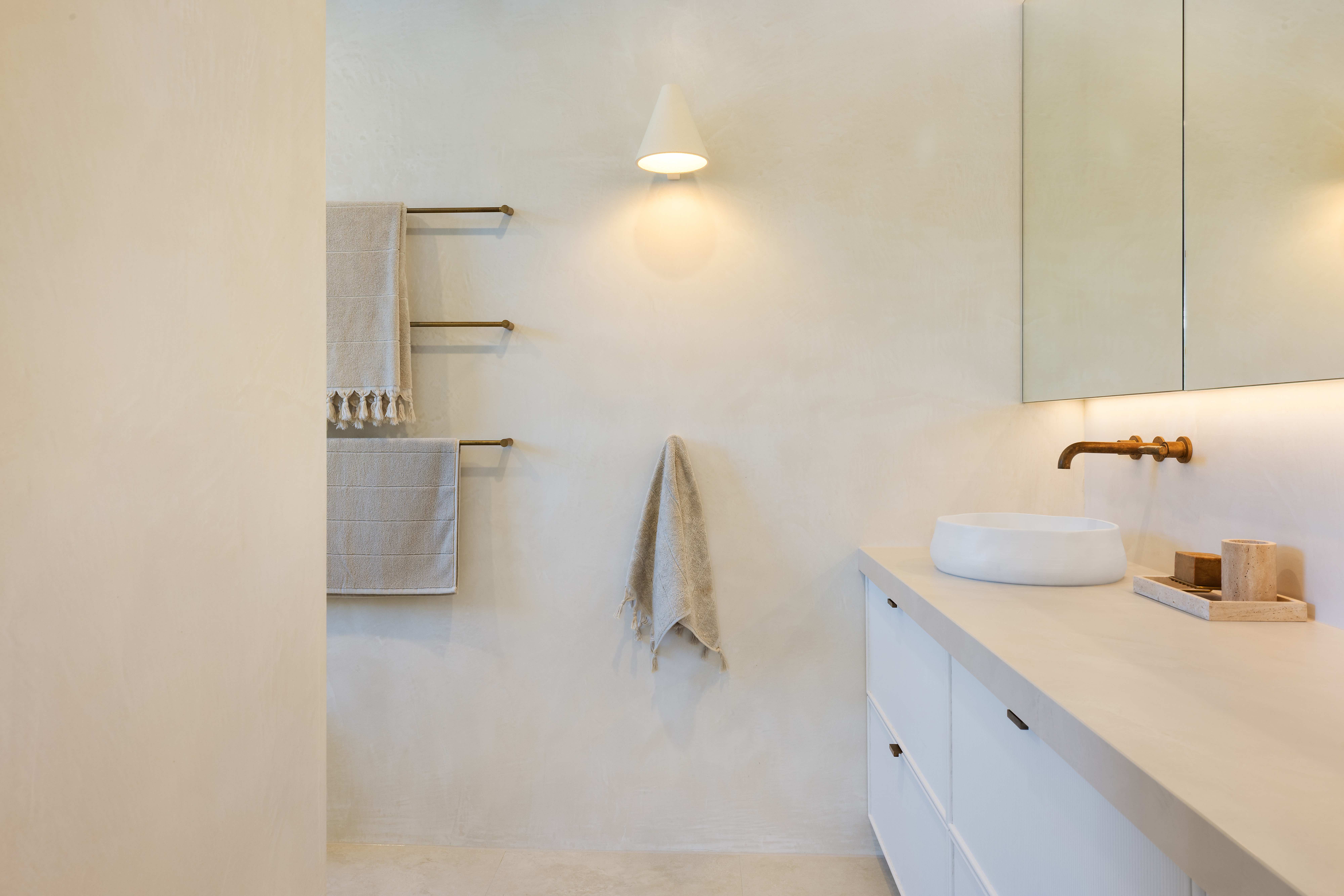 Minimalist bathroom with cone wall sconce and brass tap