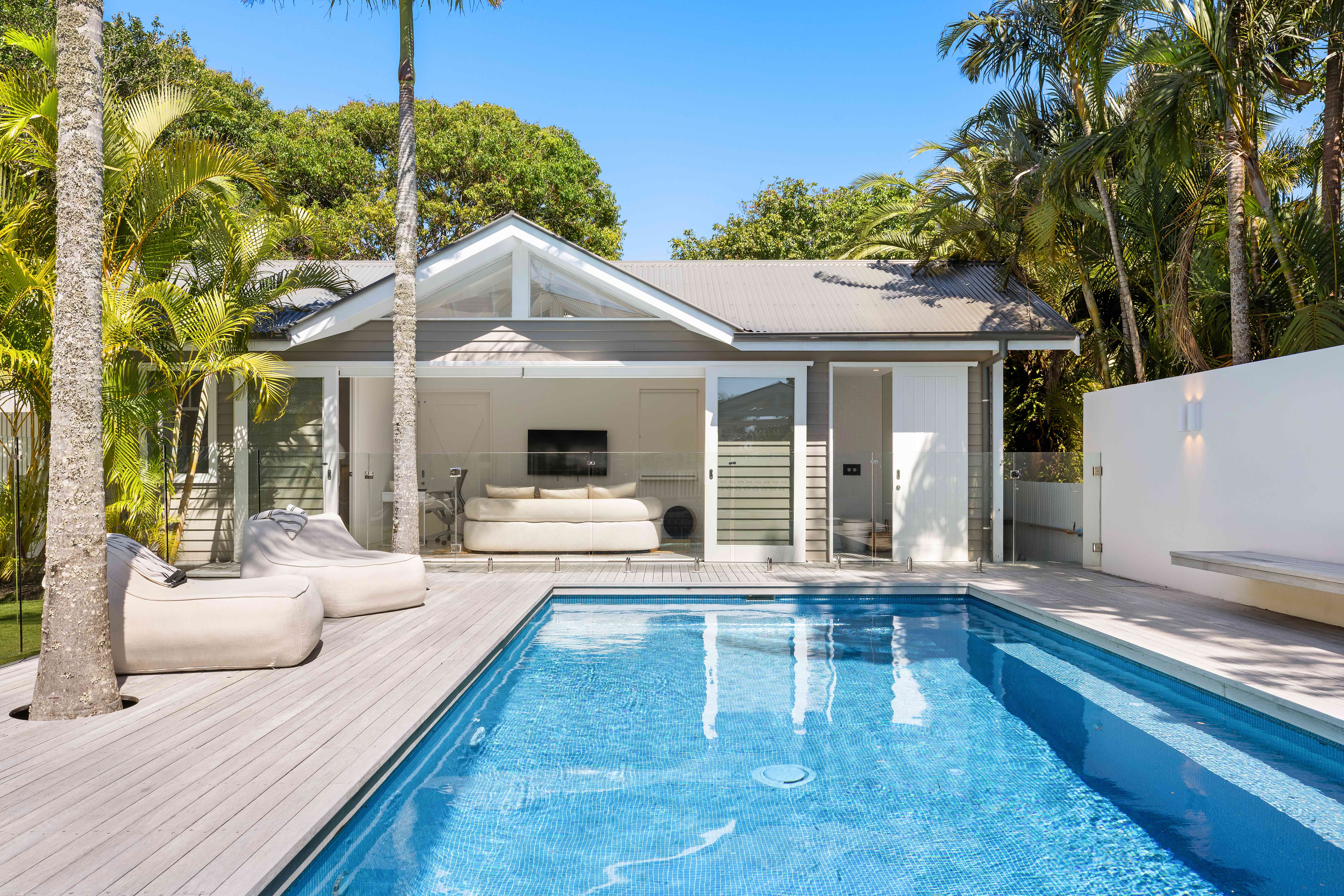 Outdoor pool area with white pavilion and palm trees