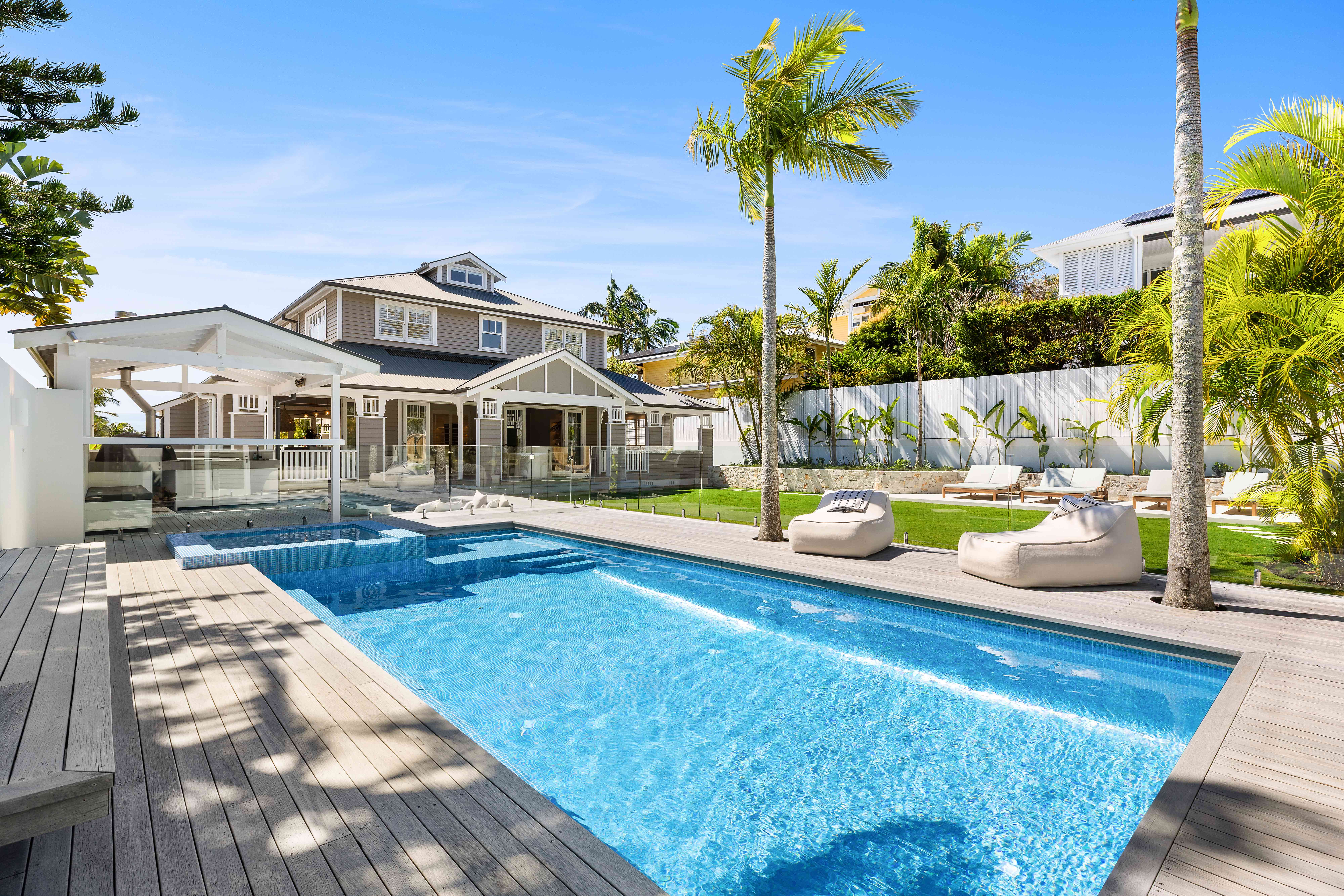 Pool area with main house, palm trees and loungers
