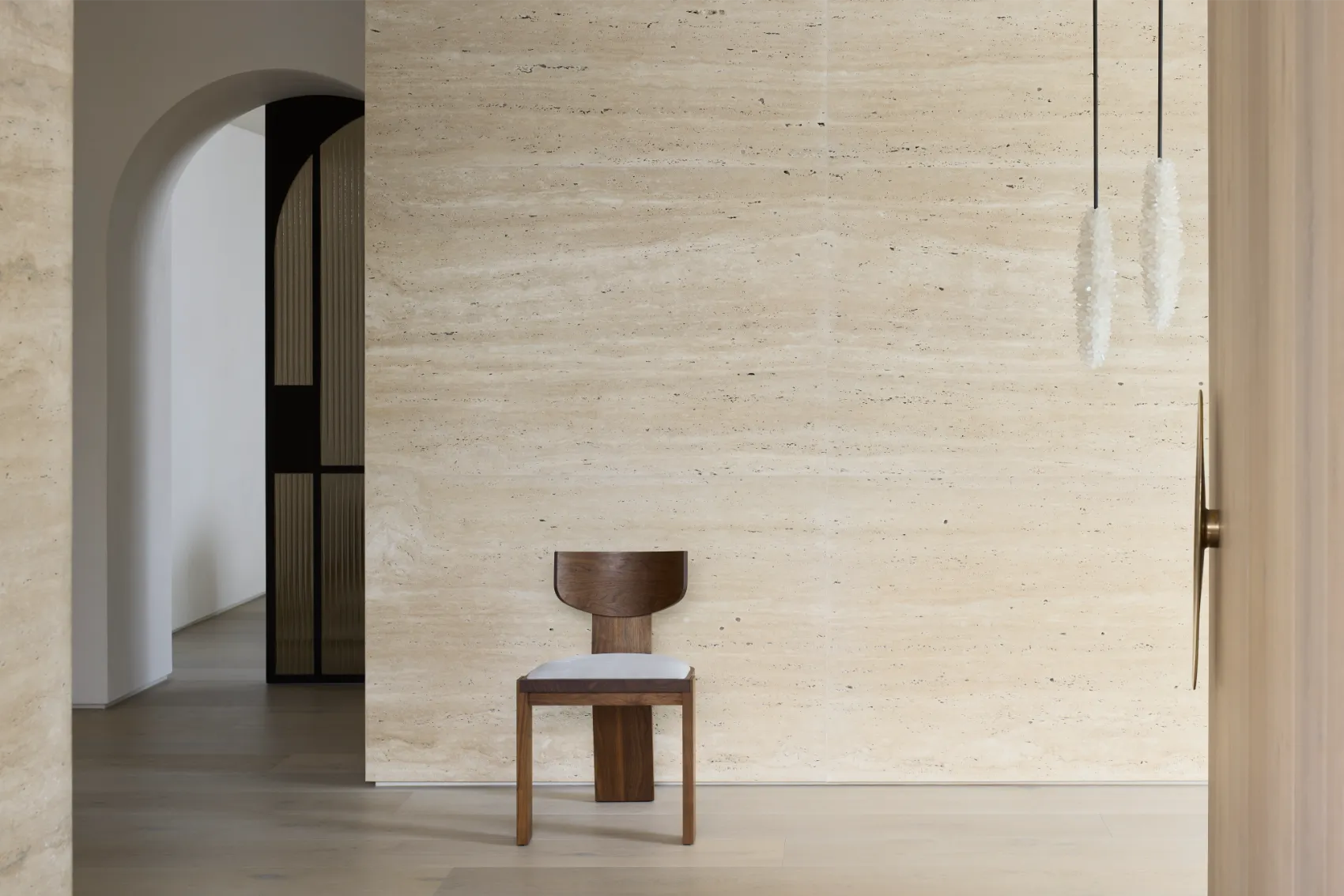 Minimalist hallway with travertine wall and wooden chair